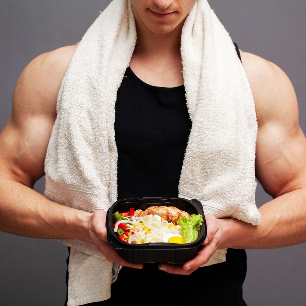very muscular man holding bowl of salad